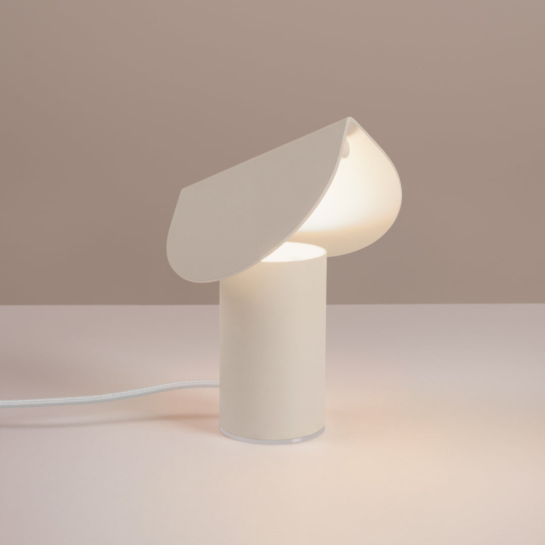 Lampe à poser BISCUIT beige allumée, sur une table
