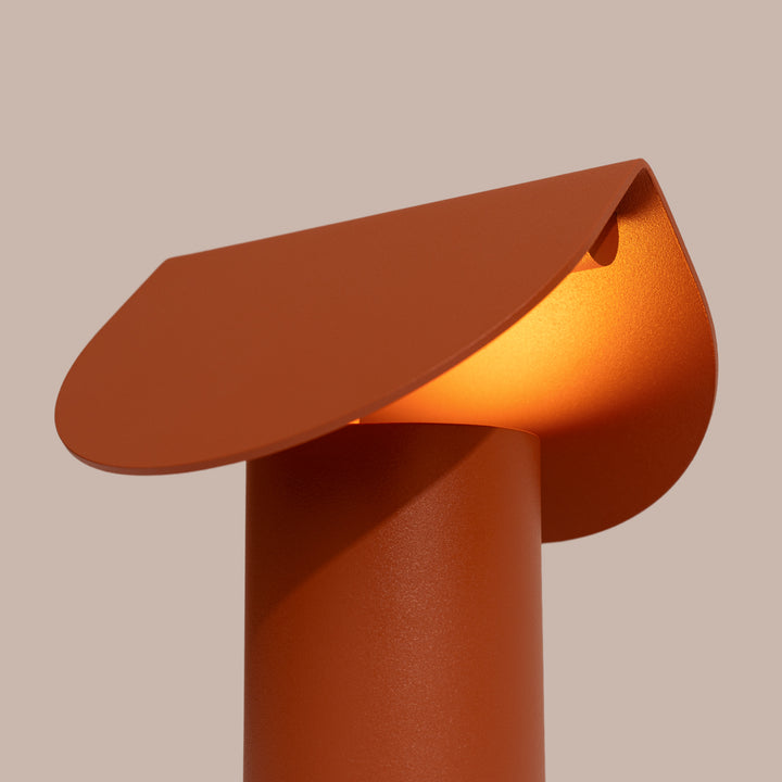 Lampe à poser BISCUIT ocre rouge allumée, vue de trois quarts