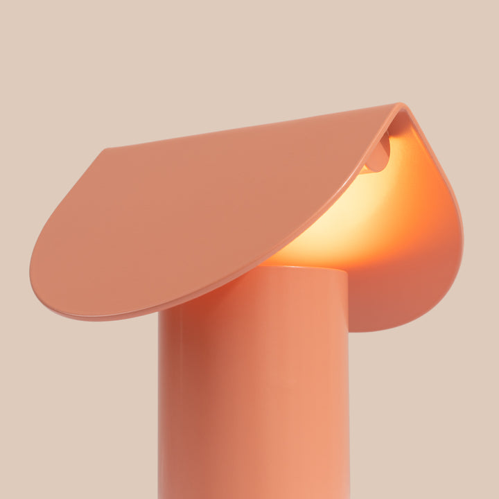 Lampe à poser BISCUIT pêche allumée, vue de trois quarts