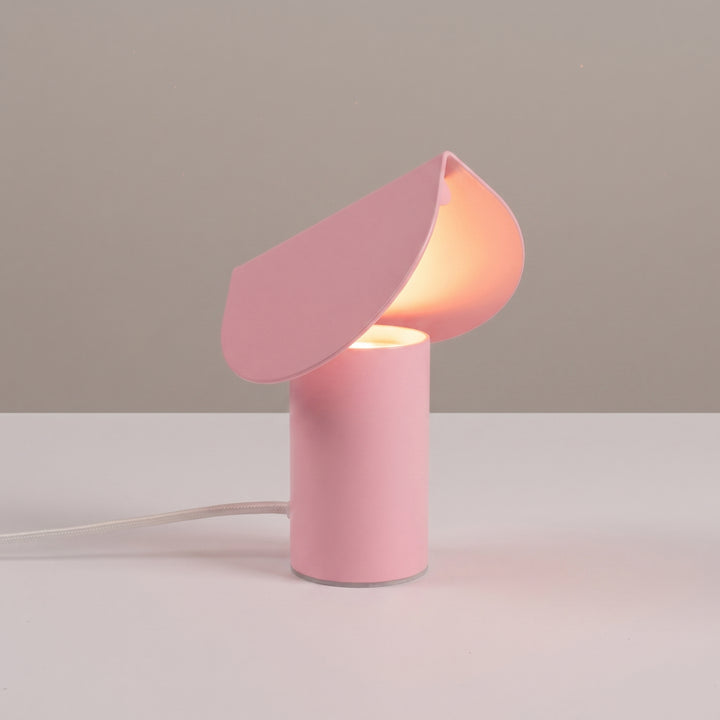 Lampe à poser BISCUIT rose allumée, sur une table