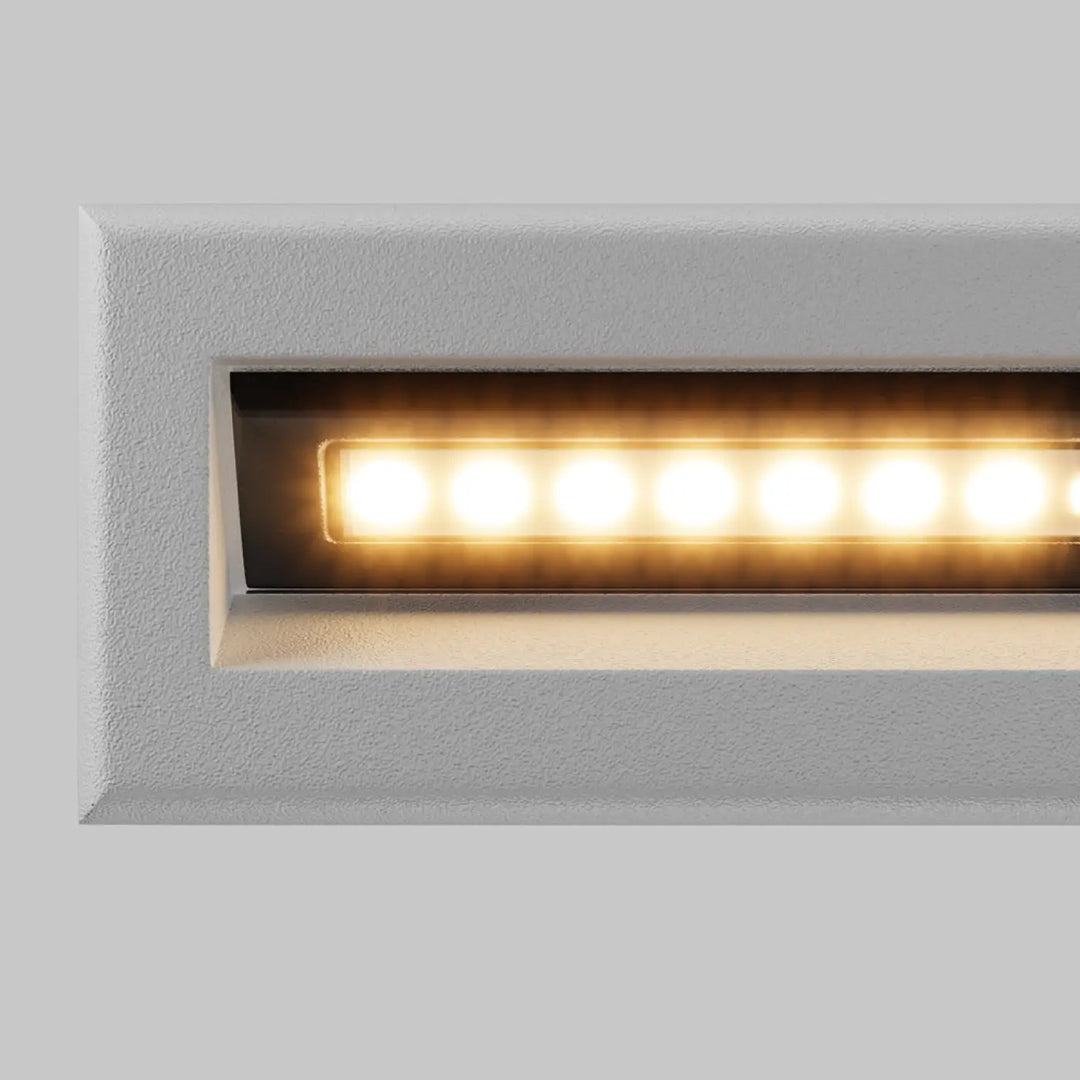 Applique encastrable moderne bosca avec finition texturée blanche et éclairage led chaud long d’une allée