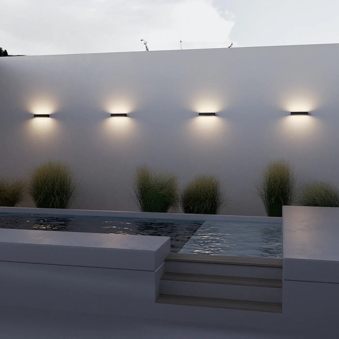 Quatre appliques extérieures barre horizontale en acier noir minimalistes avec une lumière chaude sur mur blanc