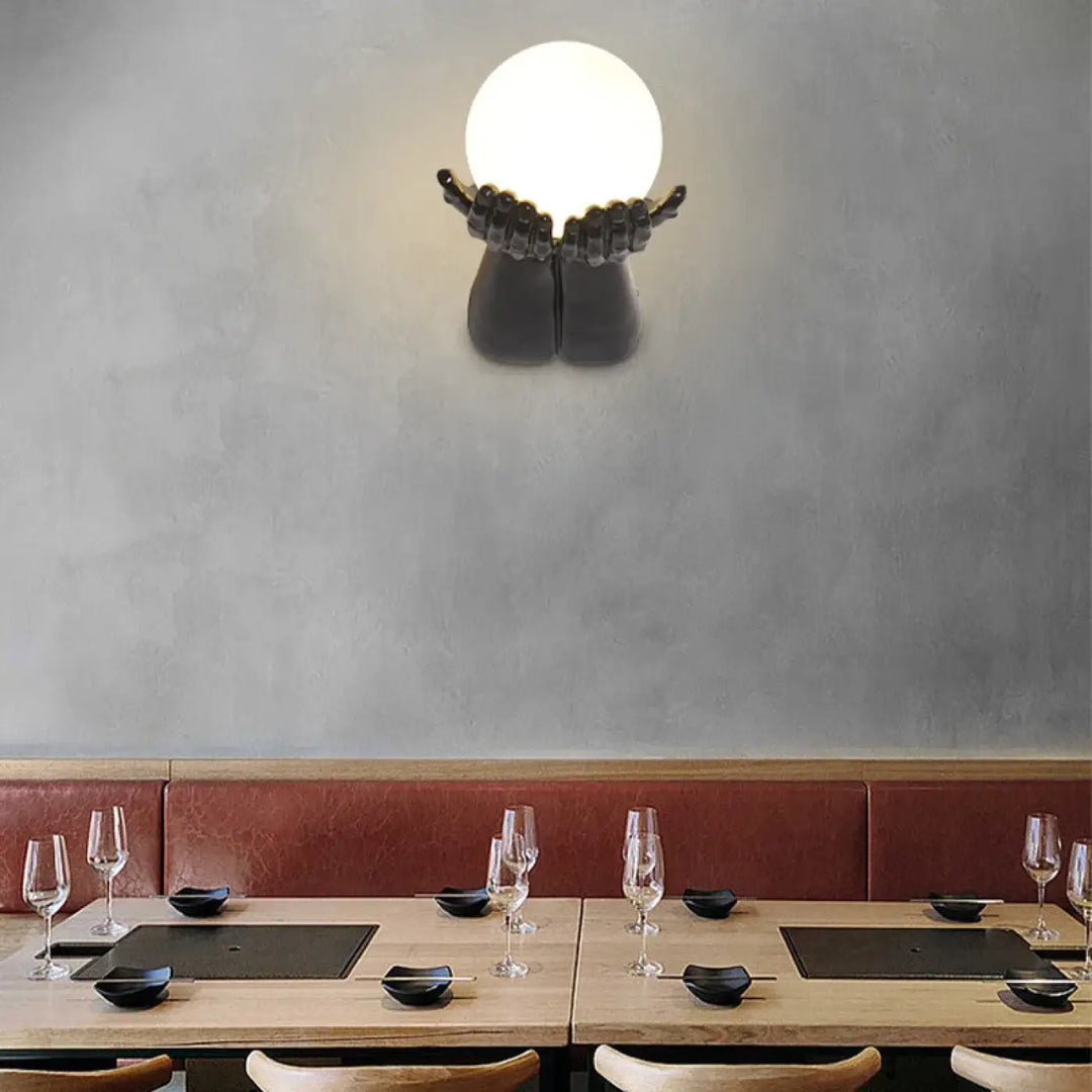 Applique murale avec brand tendu tenant une boule blanche

