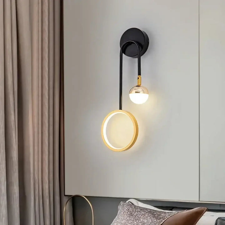 Applique murale design noire et or orialis avec bras courbé et deux globes lumineux dont un anneau suspendu lumineux chaleureux