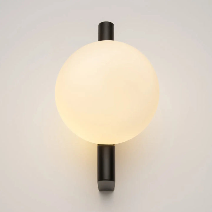 Applique murale avant garde noire avec globe en verre opale et monture géométrique diffusant une lumière chaude