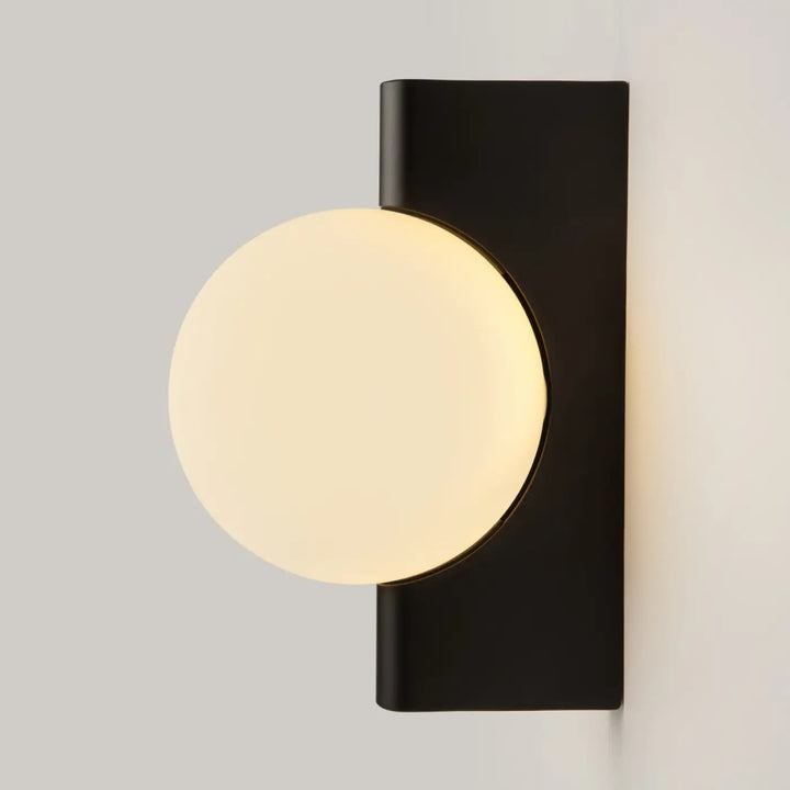 Applique murale avant garde noire avec monture géométrique et verre opale circulaire diffusant une lumière douce