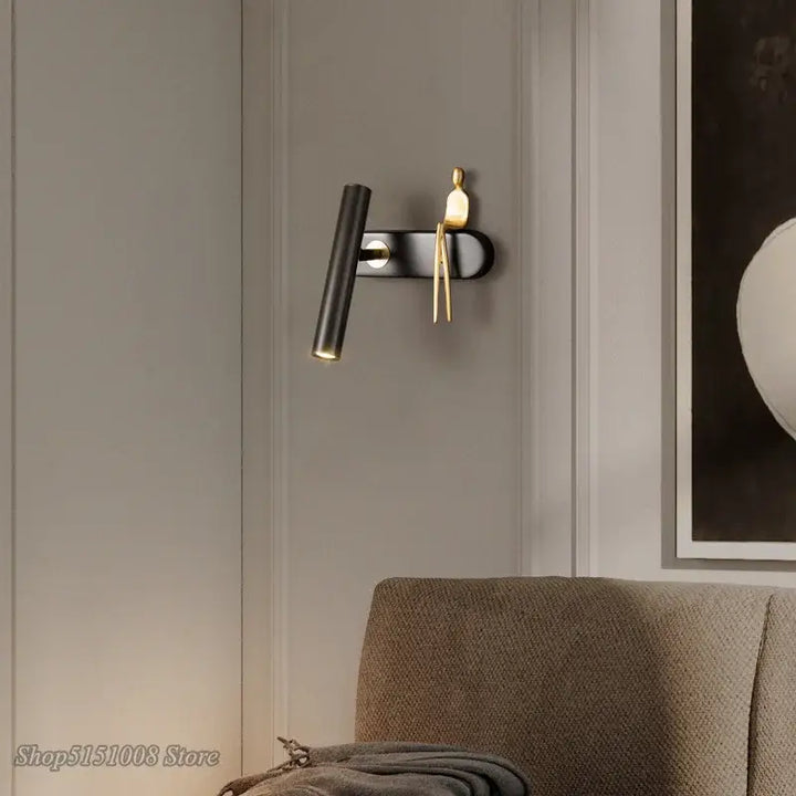 Applique murale LED noir avec un bonhomme doré assis

