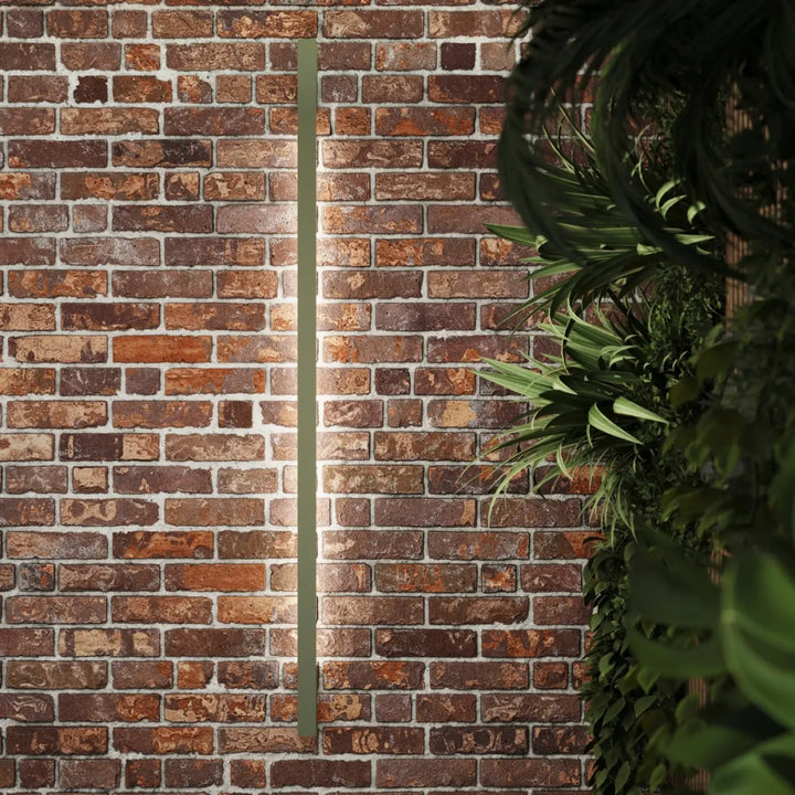 Applique murale sappo 120 led vert olive avec finition mate sage green montée sur un mur de briques rustiques