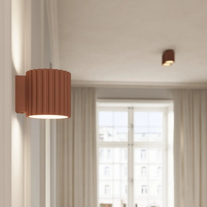Rust-colored forme unique inspirée applique murale aura moka with vertical ridges and warm diffused light output