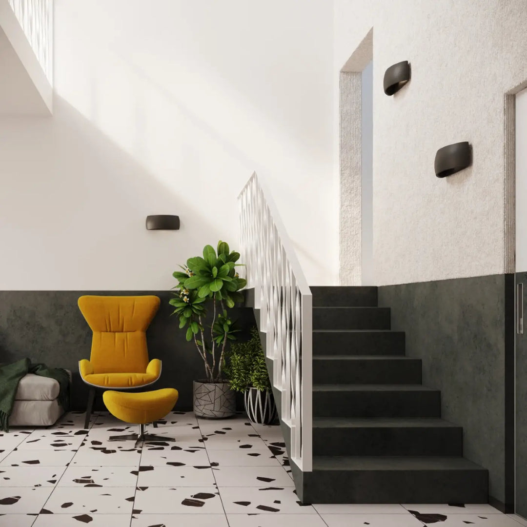 Vibrant yellow upholstered armchair with matching ottoman beside l’applique murale pontius in enduit structuré noir