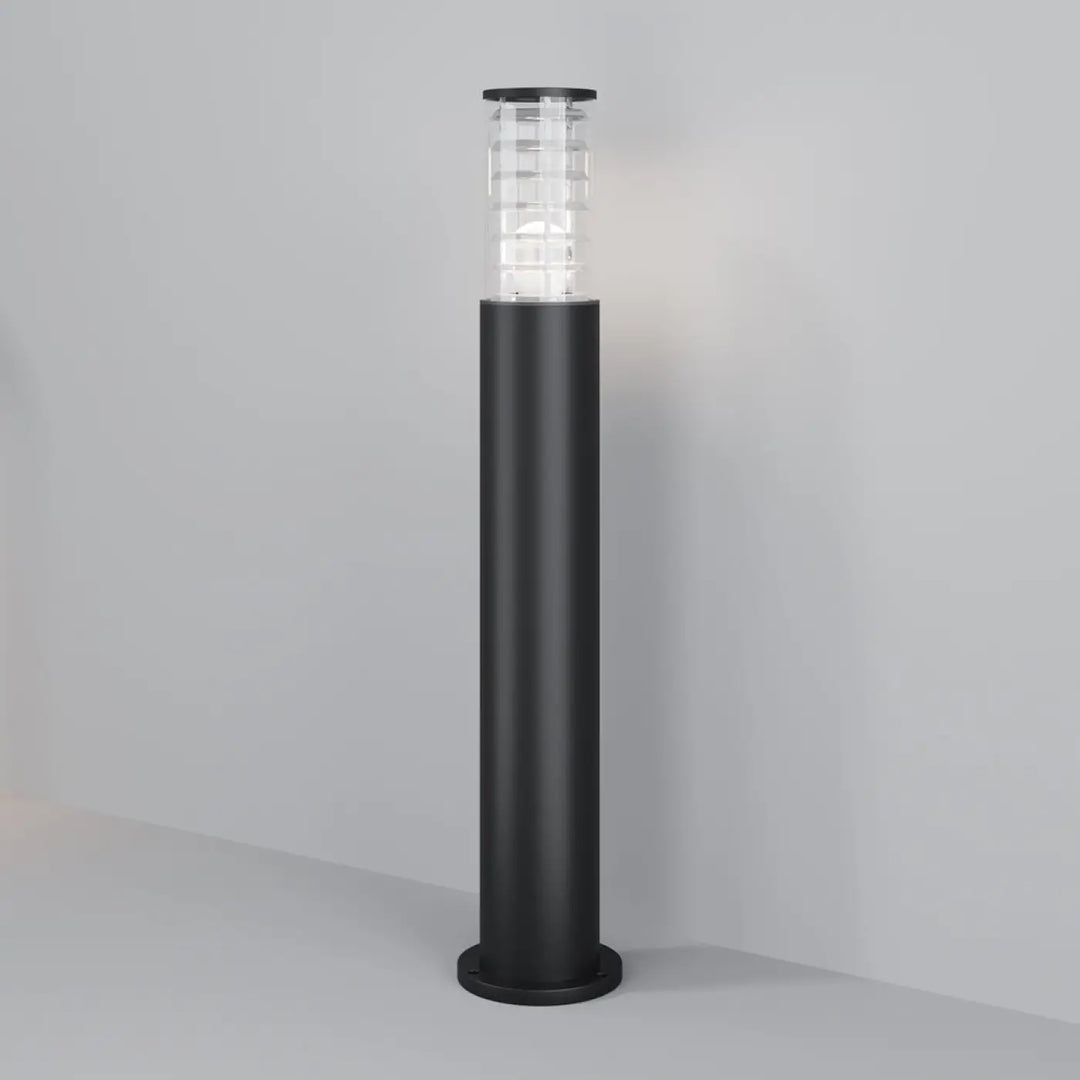 Borne extérieure bronx cylindrique noire avec verre transparent à motif géométrique et structure métallique émettant une lumière chaude