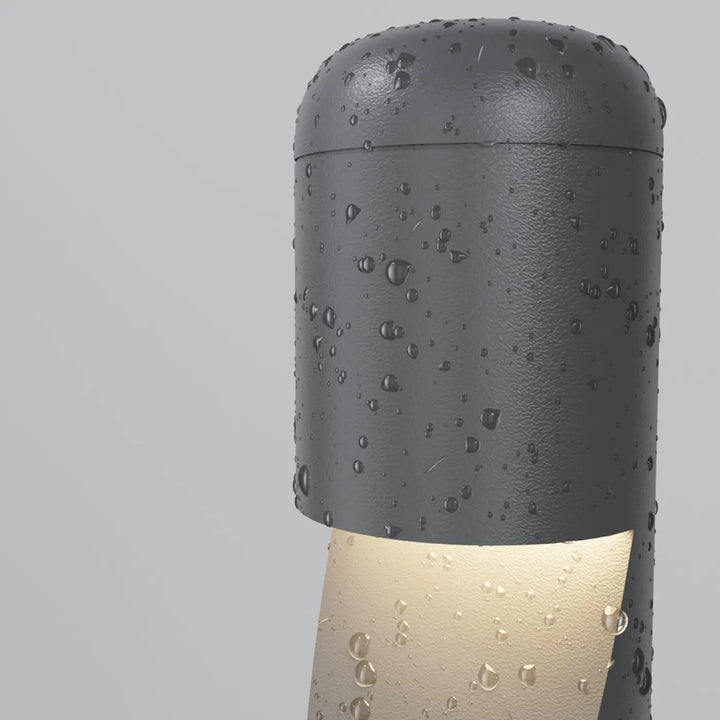 Borne extérieure cylindre étroit en acier noir avec lumière chaleureuse à la base et finition texturée gris foncé