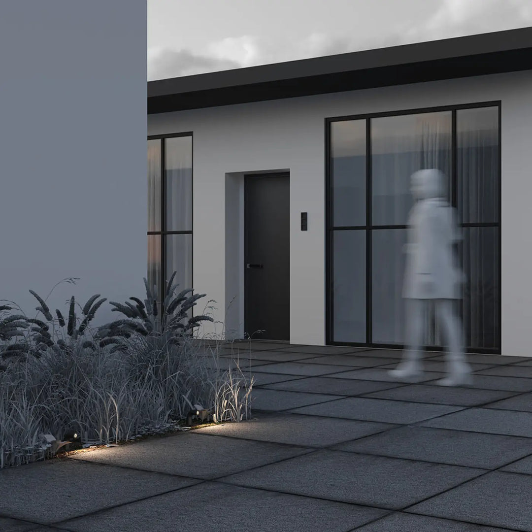 Borne extérieure led sleek cubique en aluminium noir devant maison moderne aux fenêtres noires encadrées fines