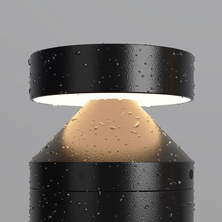 Borne extérieure version basse en acier noir avec lumière led chaude et gouttes d eau sur surface texturée cylindrique
