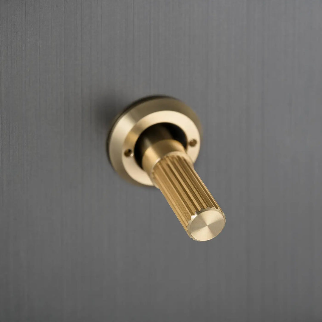 Détail d'un interrupteur à levier à gravure alignée, finitions bronze fumé et laiton #couleur_dor