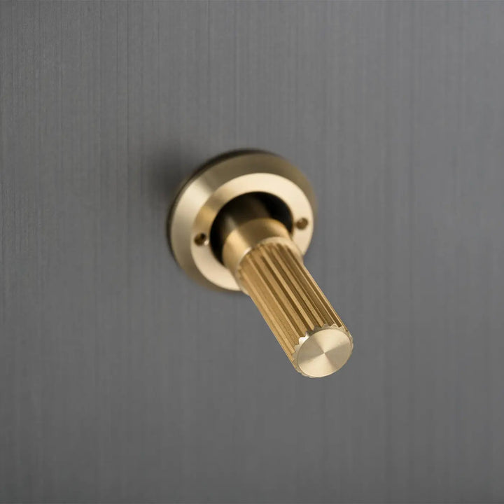 Détail d'un interrupteur à levier à gravure alignée, finitions bronze fumé et laiton #couleur_dor