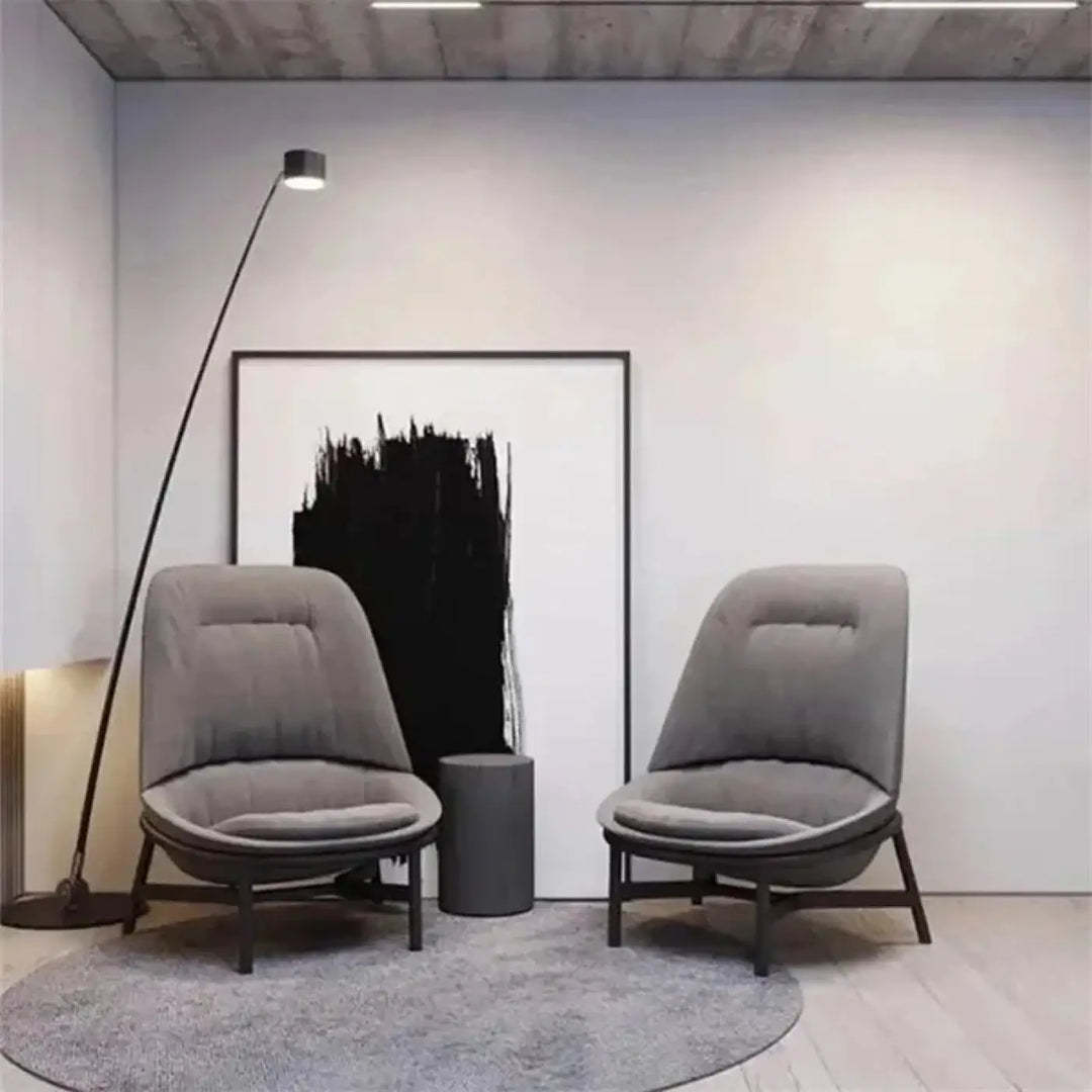 Deux fauteuils modernes en tissu gris avec pieds en bois foncé dans une pièce minimaliste avec un lampadaire design fer type nyris