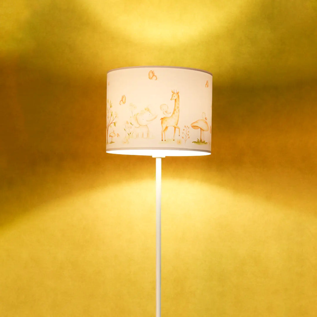 Lampadaire enfant blanc avec abat-jour cylindrique crème illustré d animaux dorés participe à créer une ambiance douce