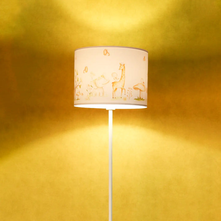 Lampadaire enfant blanc avec abat-jour cylindrique crème illustré d animaux dorés participe à créer une ambiance douce