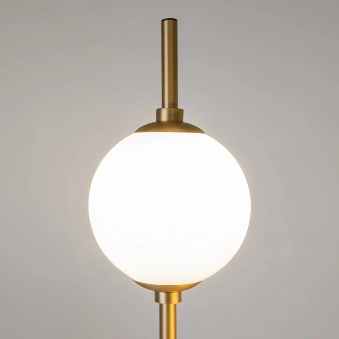 Lampadaire sixth sense en laiton avec globe sphérique en verre blanc, design élégant et lumineux pour intérieur contemporain