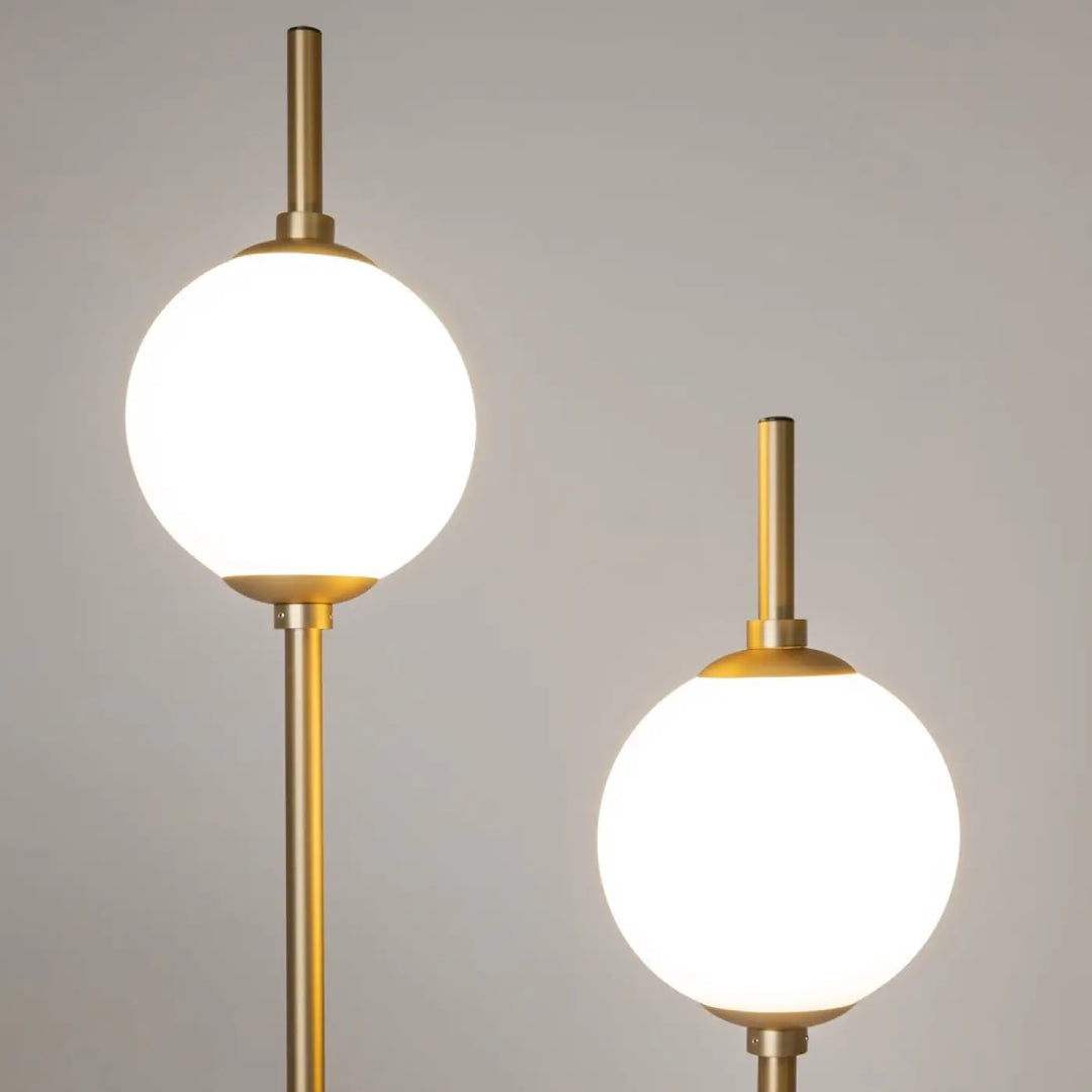 Lampadaire sixth sense avec deux globes en verre dépoli sur tiges métalliques finition or moderne et élégant