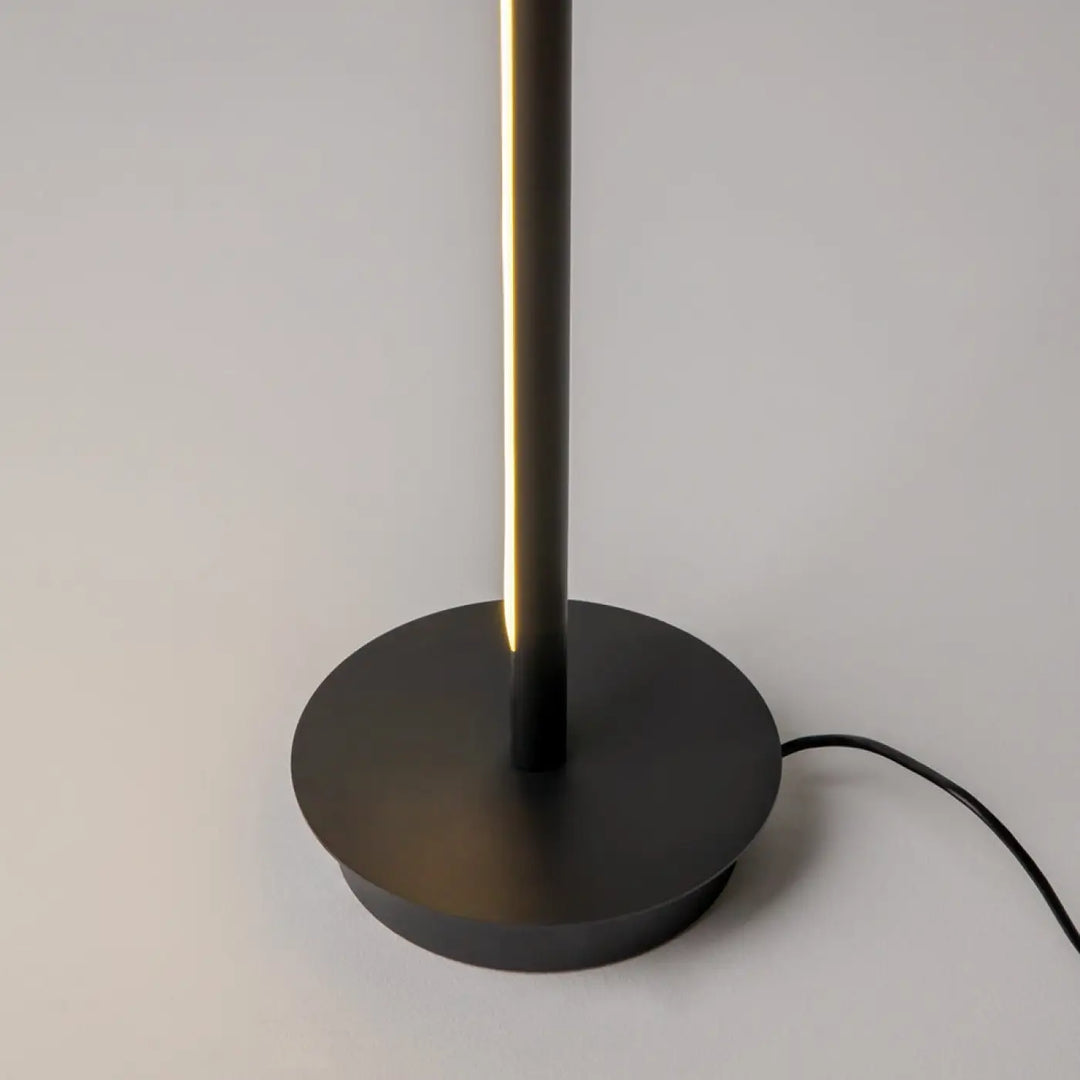 Lampadaire thin noir mat avec led intégrée émettant une lumière chaude, base circulaire pour d’un canapé élégant