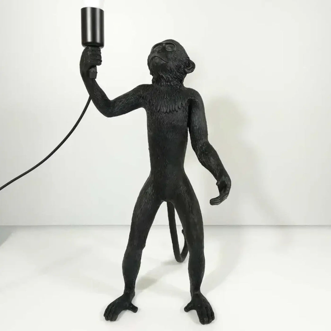 Lampadaire singe noir avec finition texturée tenant un luminaire cylindrique sur une base élégante et détails fins