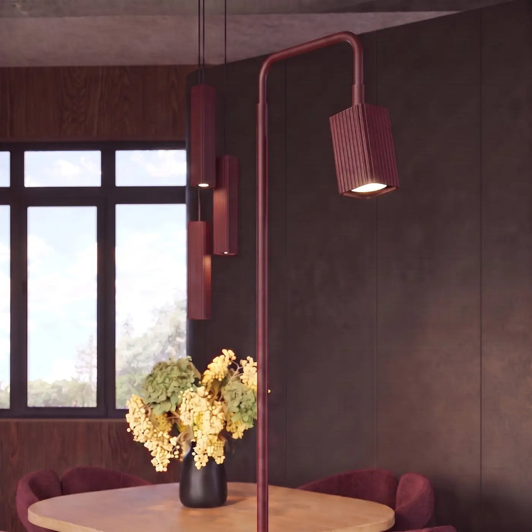 Lampadaire Rayo bordeaux à spot rainuré près d'une table à manger