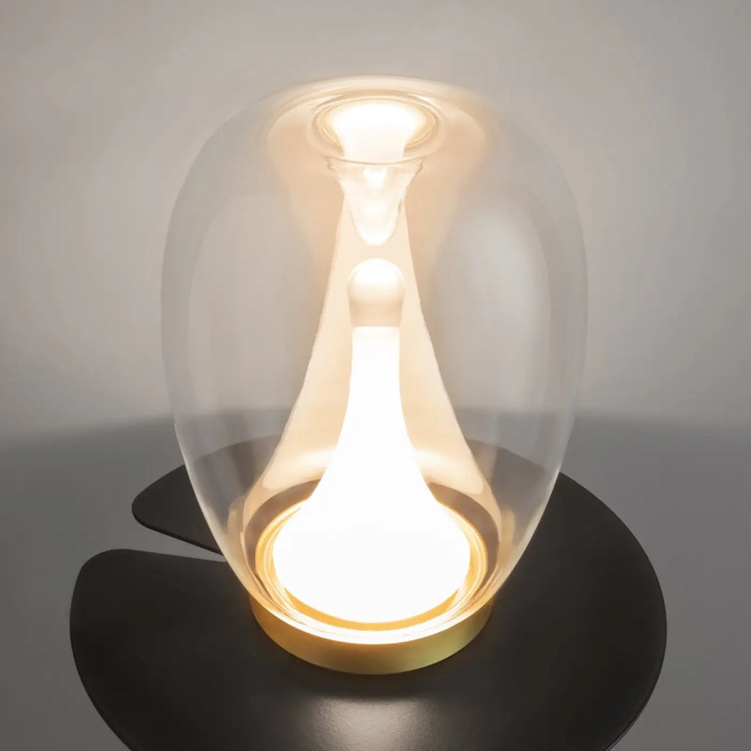 Lampe de chevet led splash avec led intégrée en verre clair en forme de goutte reposant sur base noire élégante