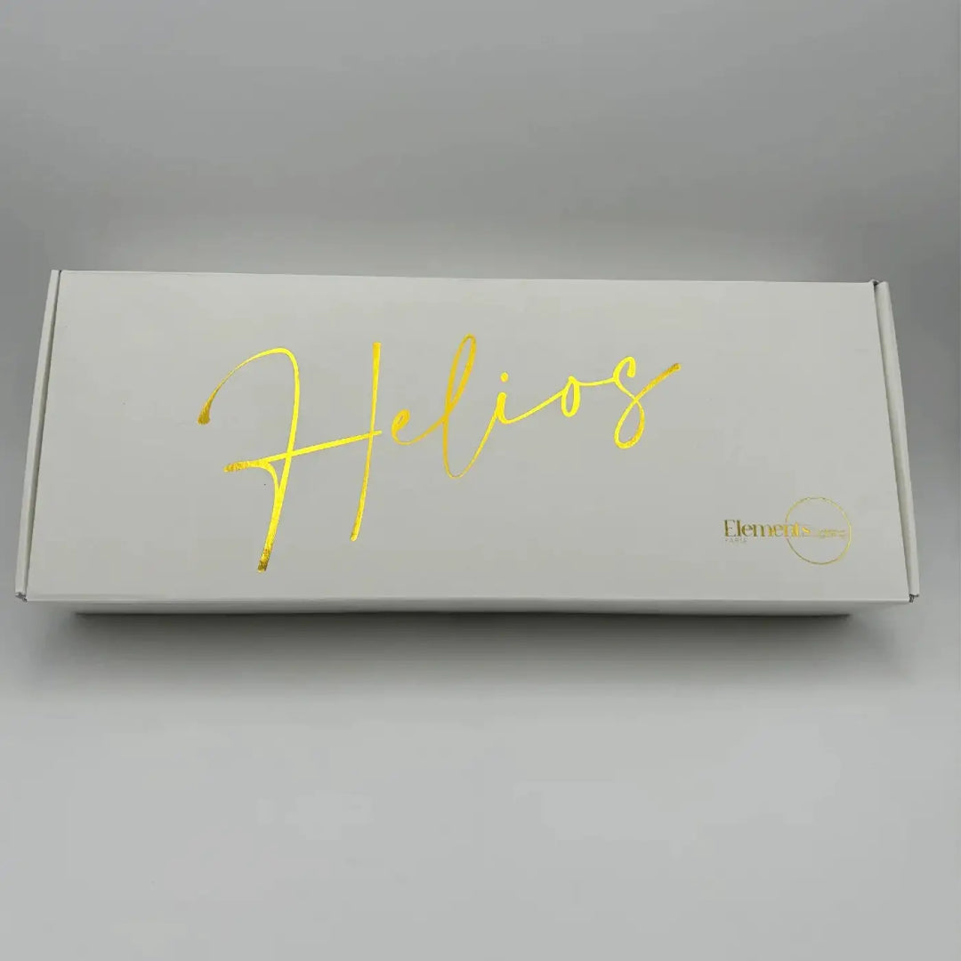 Lampe de chevet helios en boîte blanche avec lettrage doré et logo elements, un objet lumineux design et élégant
