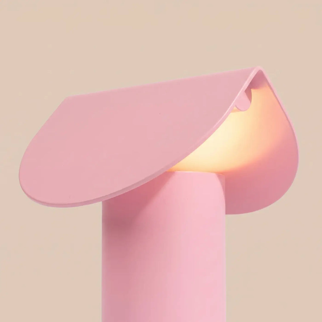 Lampe à poser BISCUIT rose allumée, vue de trois quarts
