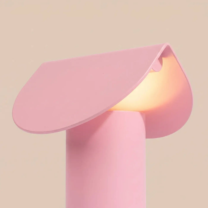 Lampe à poser BISCUIT rose allumée, vue de trois quarts