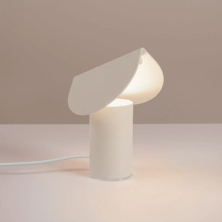 Lampe à poser BISCUIT beige allumée, sur une table