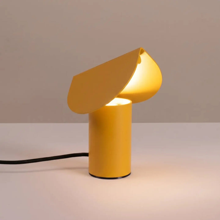 Lampe à poser BISCUIT jaune allumée, sur une table