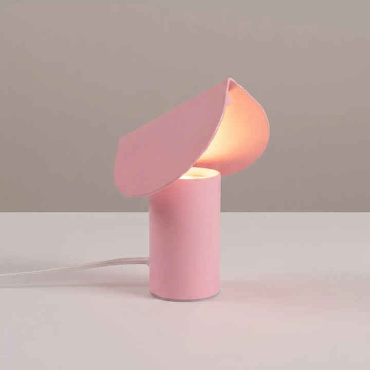 Lampe à poser BISCUIT rose allumée, sur une table