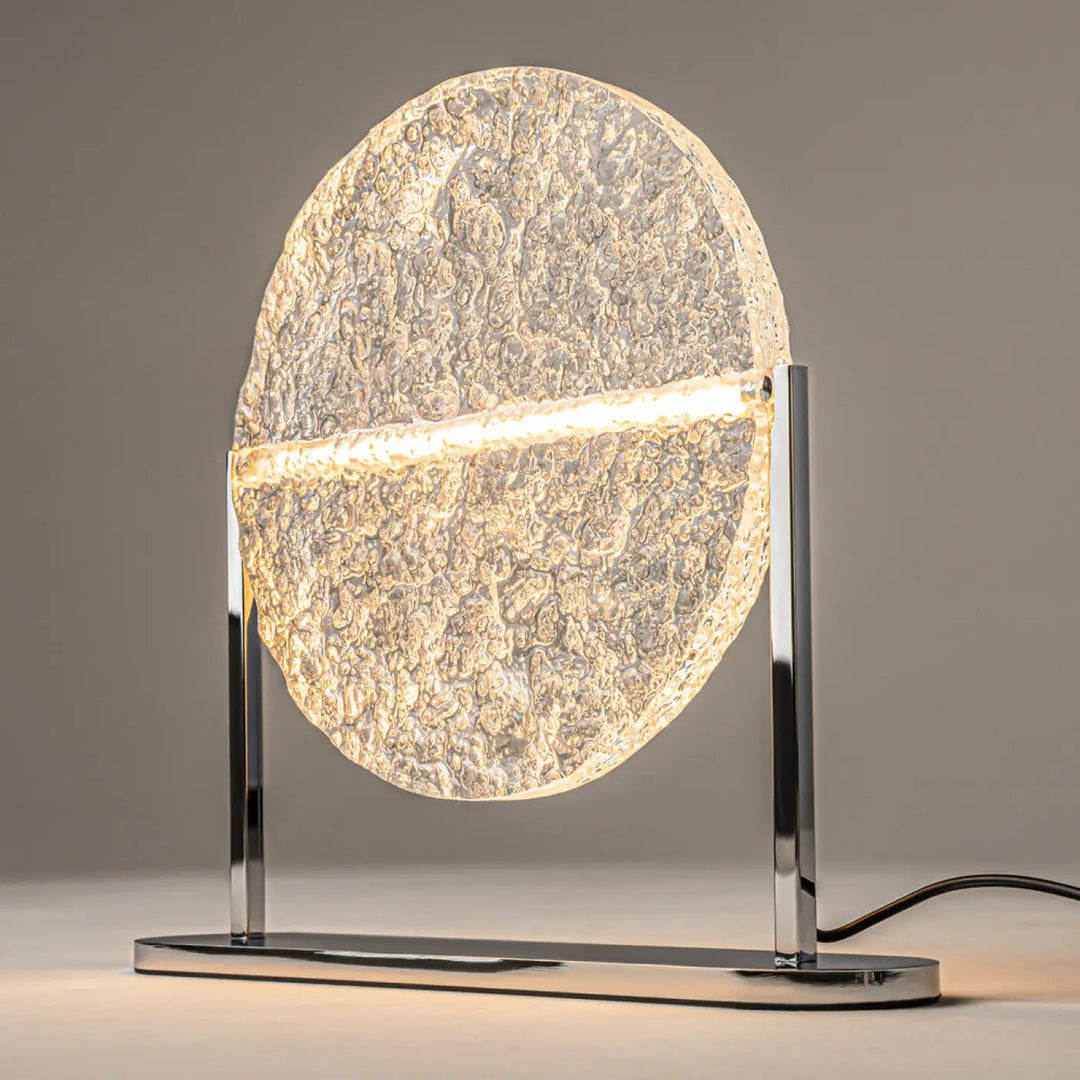 Lampe à poser mangata en verre martelé avec structure argentée et abat-jour circulaire texturé diffusant une lumière chaude
