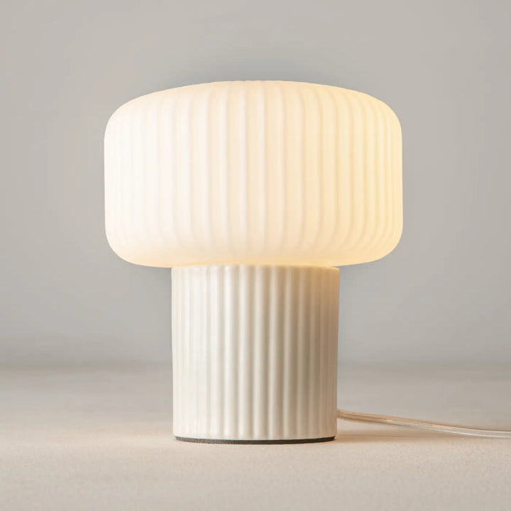 Lampe de chevet omaggio en céramique blanche avec base cylindrique et lumière douce émise par un verre côtelé crème