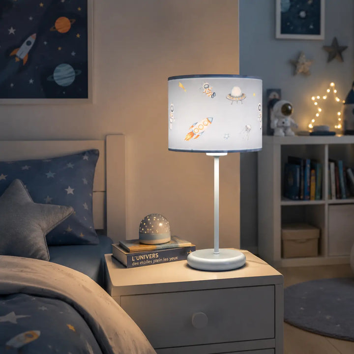 Lampe de table sweet dreams avec abat-jour blanc cylindrique décoré d illustrations spatiales colorées sur base argentée pour chambre d’enfant et décoration intérieure table bleu