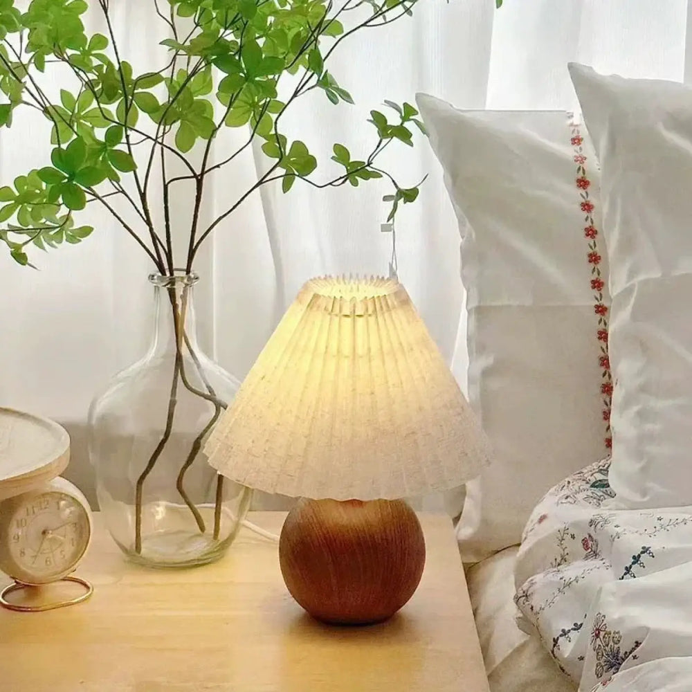 Lampe de chevet en bois chaleureux avec abat-jour plissé en tissu écru offrant une lumière douce pour décoration intérieure