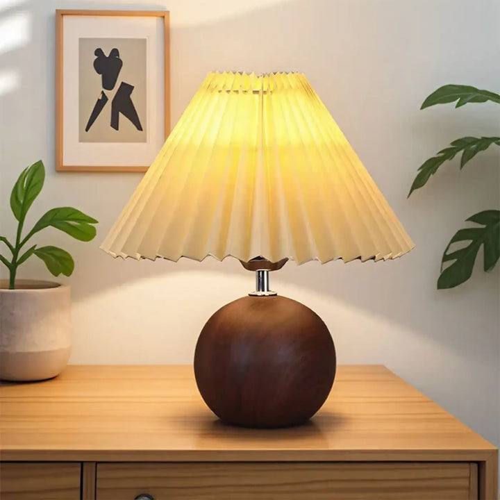 Lampe de chevet pliplisse avec abat-jour plissé chaud sur base en bois foncé pour une lumière douce et décoration intérieure
