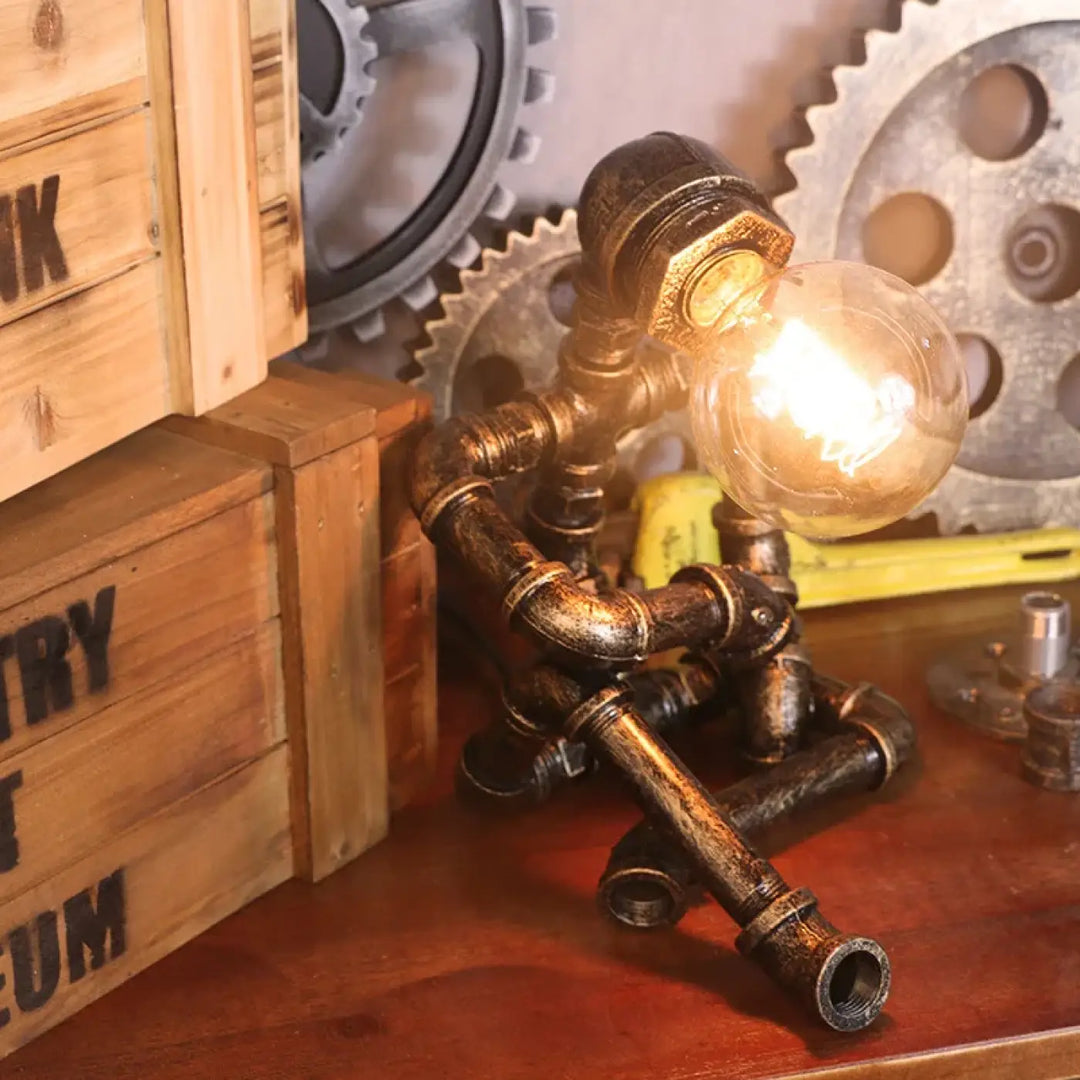 Lampe de table ironix en métal sombre vieilli style industriel avec ampoule filament allumée pipe robot design unique