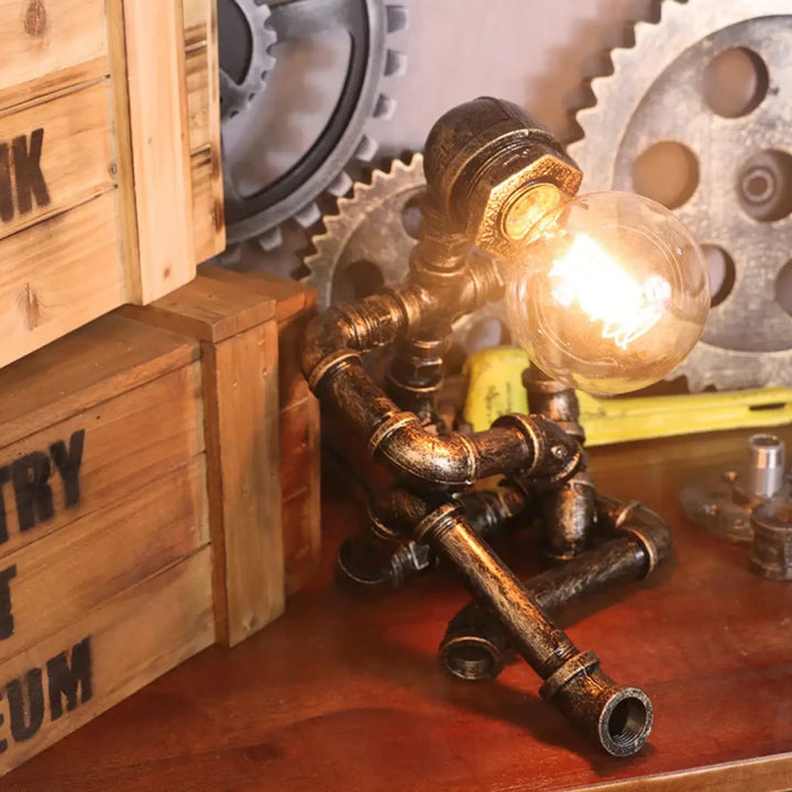 Lampe de table ironix en métal sombre vieilli style industriel avec ampoule filament allumée pipe robot design unique