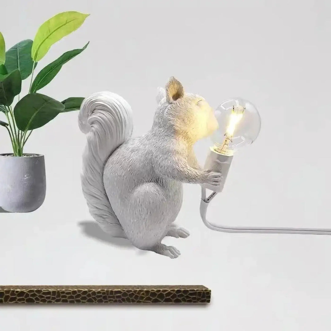 Lampe de table écureuil en résine blanche avec finition texturée tenant une ampoule edison illuminée design écureuil
