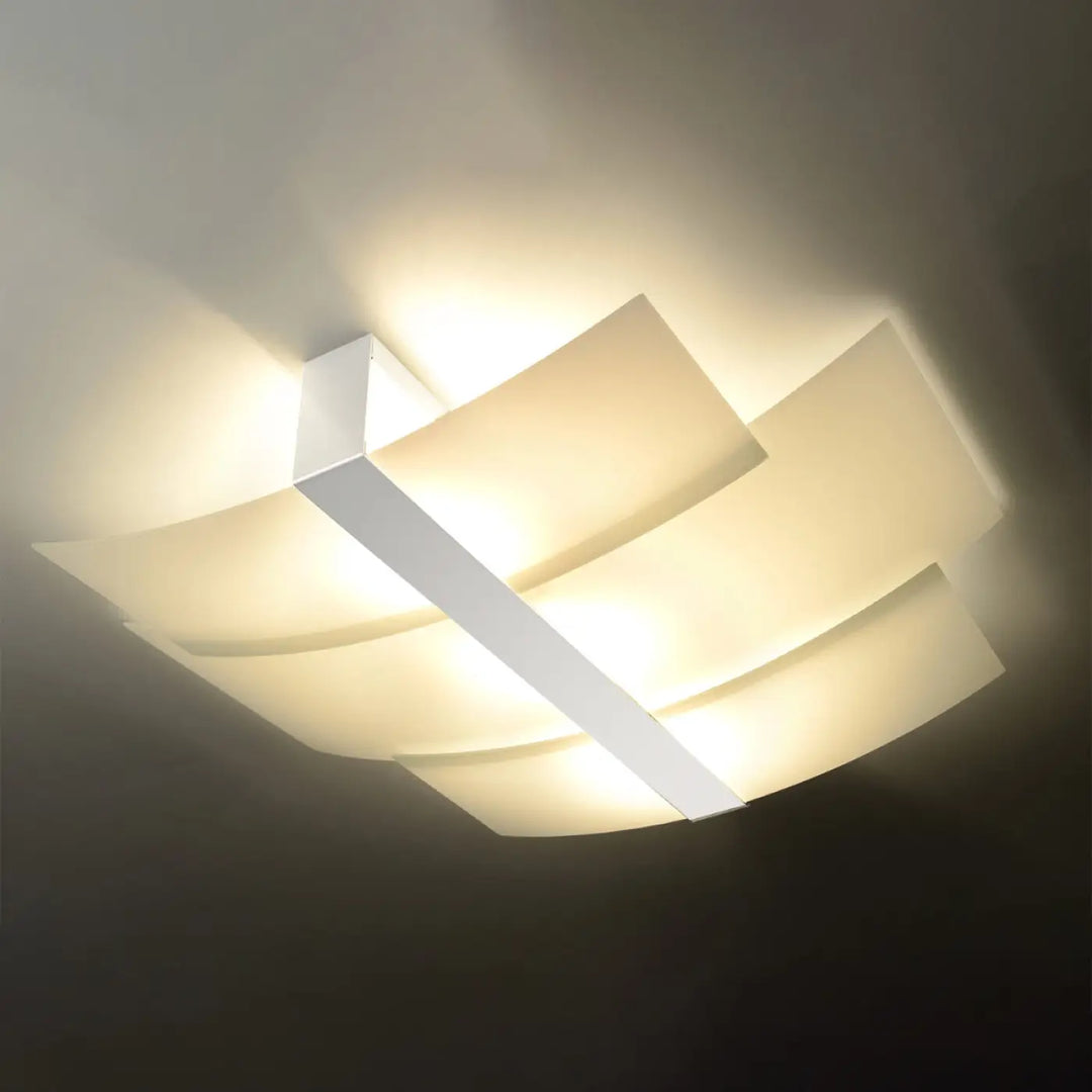 Luminaire plafonnier celia blanc avec panneaux géométriques superposés émettant une lumière chaude design intemporel