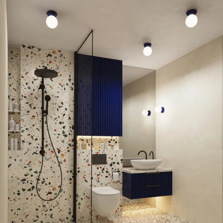 Luminaire plafonnier lampe zori en ultramarine dans une salle de bain moderne avec murs en terrazzo et meuble navy blue, belle décoration et qualités esthétiques