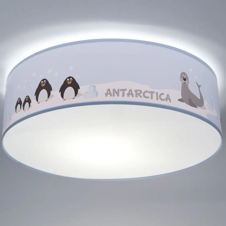 Luminaire plafonnier enfant avec abat-jour bleu clair illustré de pingouins noirs et un phoque sur fond antarctique