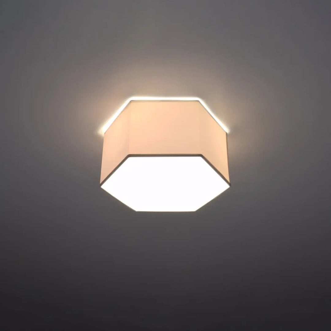 Luminaire plafonnier sunde 15 blanc avec forme géométrique hexagonale et abat-jour en tissu beige diffusant une lumière chaude