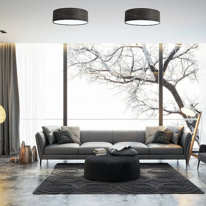 Luminaire plafonnier rond noir avec canapé en cuir gris et coussins en tissu noir et motifs gris