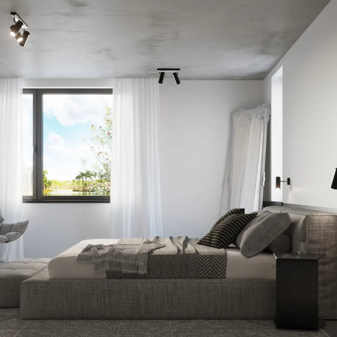 Luminaire plafonnier direzione 1 noir avec éclairage élégant au-dessus d’un lit plateforme gris en tissu texturé