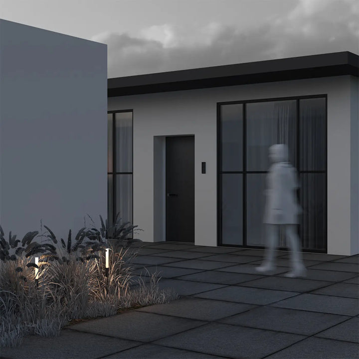 Luminaire extérieur flare tige fine en aluminium noir devant maison moderne avec porte grise et fenêtres noires